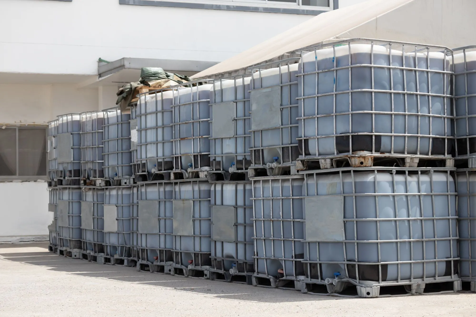 IBC totes stacked outside at a chemical distribution facility